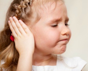 little girl frowning and holding her ear