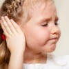 little girl frowning and holding her ear
