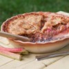 rhubarb pie with a slice gone and stalks next to pie pan