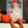 Little girl dressed as a chicken sitting on the front porch.