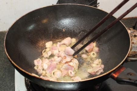stirring shallots in wok with chopsticks