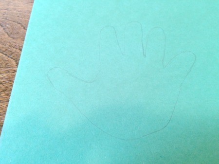 trace hand on green paper