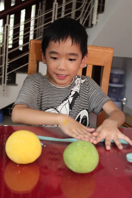 boy rolling a rope of dough