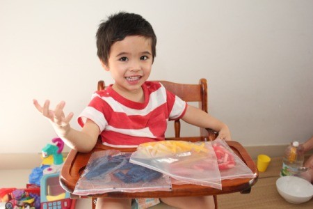 three bags of colored pasta on table in front of child