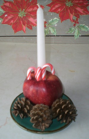 cored apple with candle and candy canes surrounded by pine cones