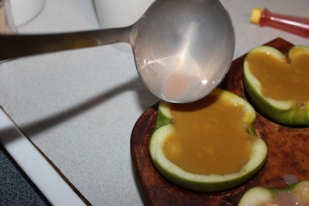 Pouring the flavored Jello into the apple halves.