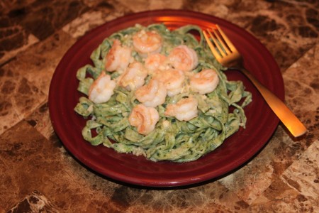 A plate of spinach pasta with shrimp.