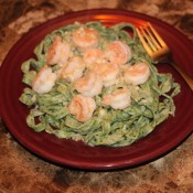 A plate of spinach pasta with shrimp.