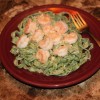 A plate of spinach pasta with shrimp.
