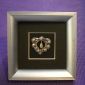 A silver frame with a decorative pin.