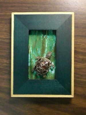 A turtle pin framed in green.