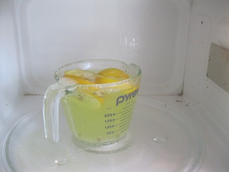 Lemon and Baking Soda for Cleaning Microwave - A measuring cup with cut up lemons, water and baking soda.