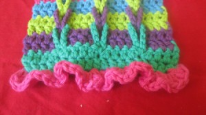 A multi colored crocheted scarf with connecting loops.