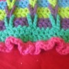 A multi colored crocheted scarf with connecting loops.