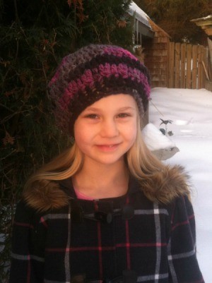 A girl wearing a crocheted beret outside in winter.