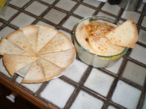 A bowl of homemade hummus, served with flavored tortilla chips.