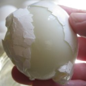 A hard boiled egg being peeled.