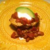 A dish of tamale pie, topped with salsa, sour cream and avocado.