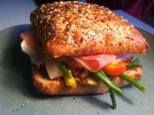 A prosciutto sandwich with several different vegetables.