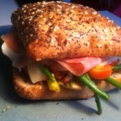 A prosciutto sandwich with several different vegetables.
