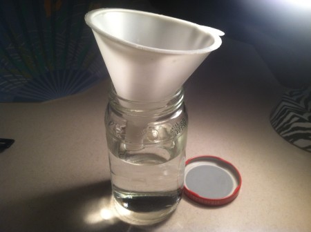 A funnel inside a small jar with water.