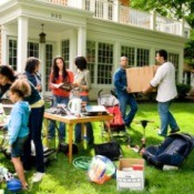 A yard sale with many people shopping.