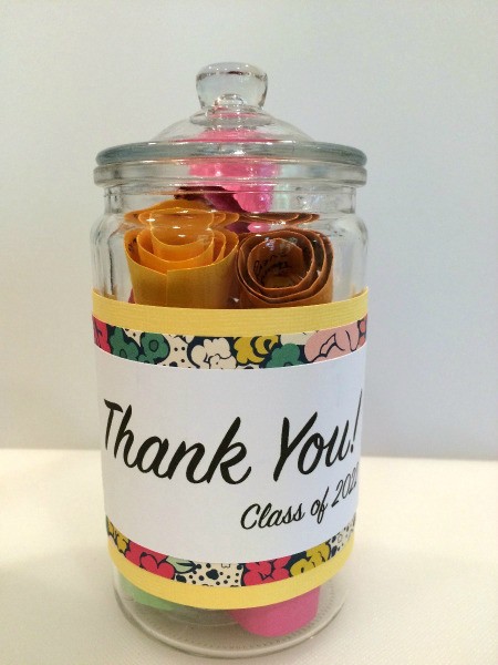 glass jar with lid containing brightly colored rolls of paper with messages for teacher