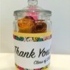 glass jar with lid containing brightly colored rolls of paper with messages for teacher