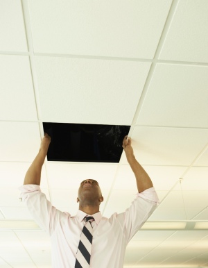 A man replacing a ceiling tile.