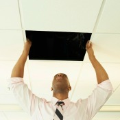 A man replacing a ceiling tile.