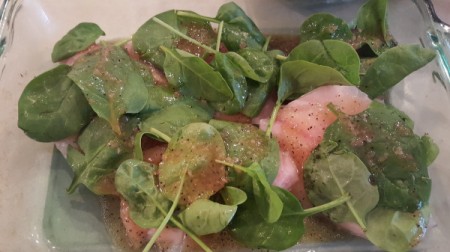 Adding spinach to the marinated tilapia.