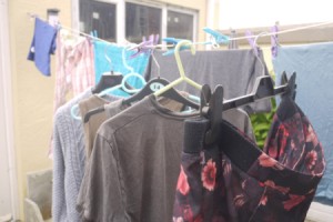 A row of clothing on hangers, drying on a clothesline.