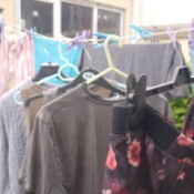 A row of clothing on hangers, drying on a clothesline.
