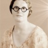 An old fashioned black and white photo of a woman in glasses.