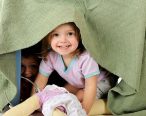 children playing in a playhouse made from a table and blanket