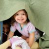 children playing in a playhouse made from a table and blanket