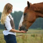 young woman feeding a treat to her horse