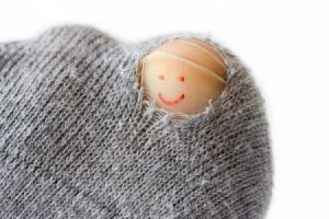 hole in sock exposing big toe nail with smiley face