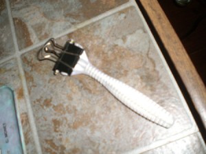 A binder clip over the blade portion of a disposable razor.