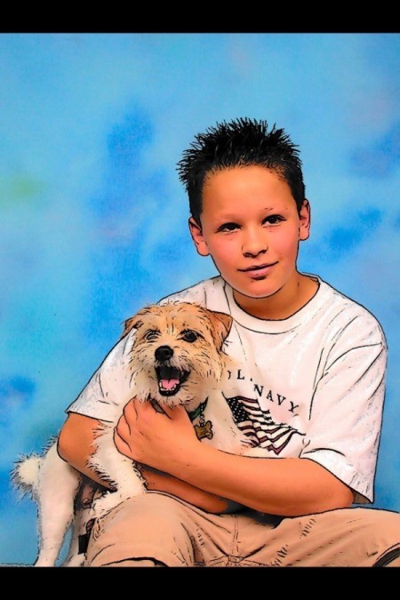 A Jack Russell terrier sitting with a boy having a picture taken.