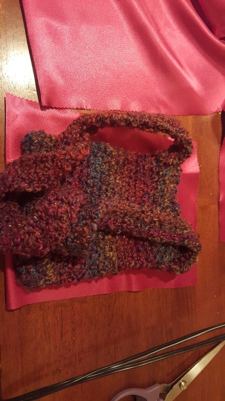 A handmade crocheted purse next to lining fabric.