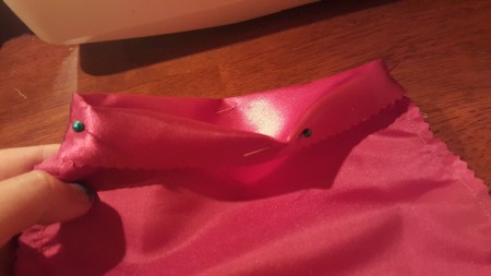 Pink fabric cut and pinned for sewing.