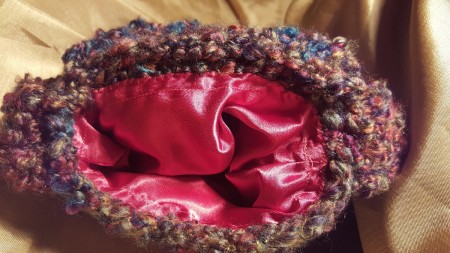 A handmade purse with a pink fabric lining.