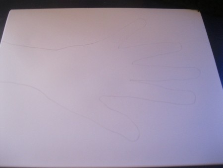 A piece of white paper with a hand traced on it.