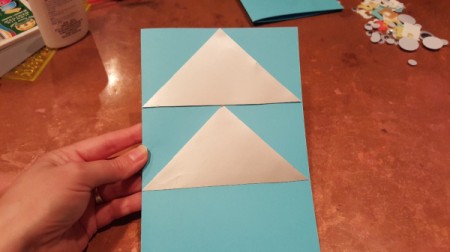 Two paper triangles glued to the front of the folded paper card.