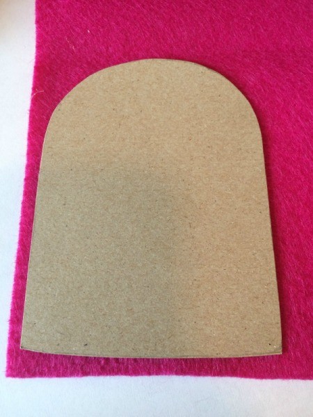A rounded brown felt shape on top of a red felt piece.