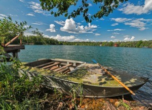 small boat on a lake with green algae on top and sides