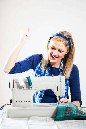 Photo of a woman with a broken sewing machine that won't go in reverse.