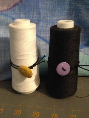 Using Large Spools on a Sewing Machine - large spool of white and one of black thread fitted with button and elastic
