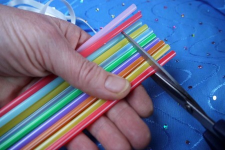 Cutting straws to make small sections for the necklace.